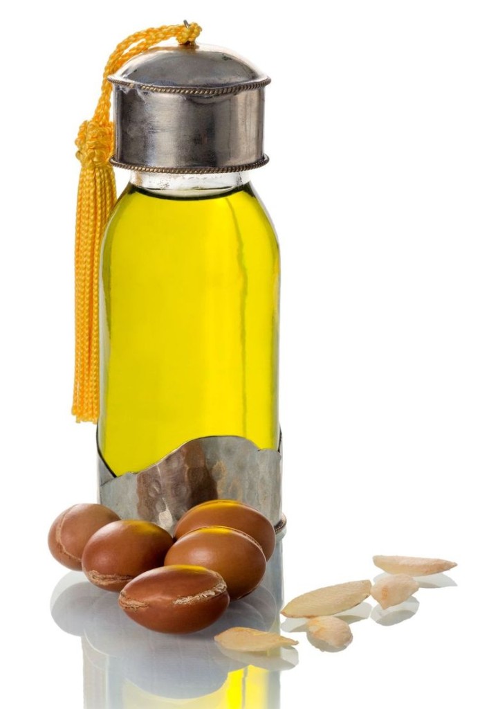 Glass bottle of argan oil with nuts and seeds